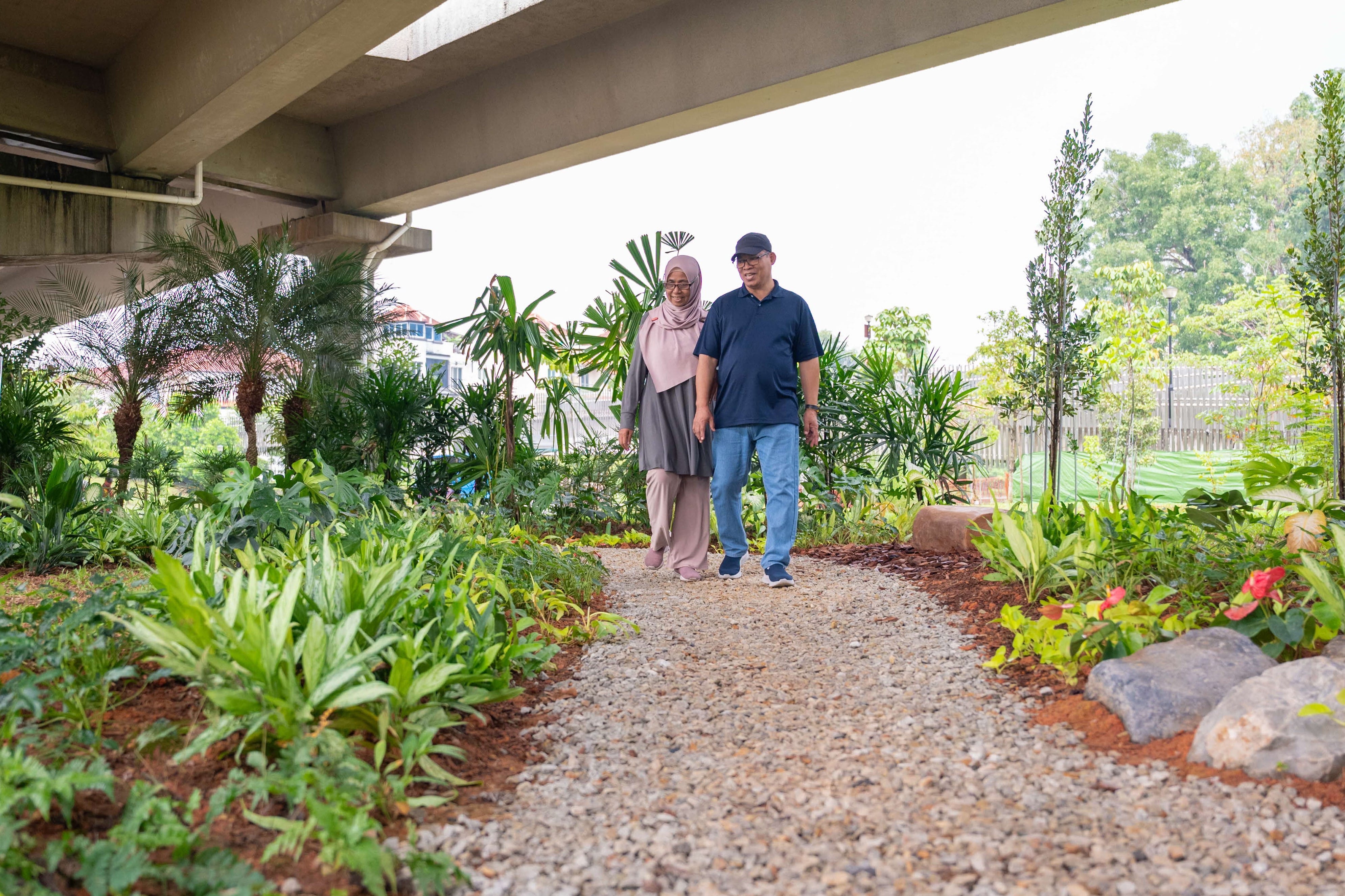 Person walking through park underneath expressway viaduct